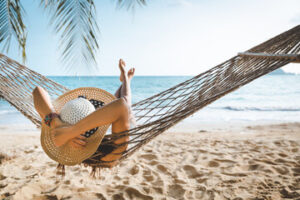 Alt Image Text: Woman relaxing in a hammock on the beach.